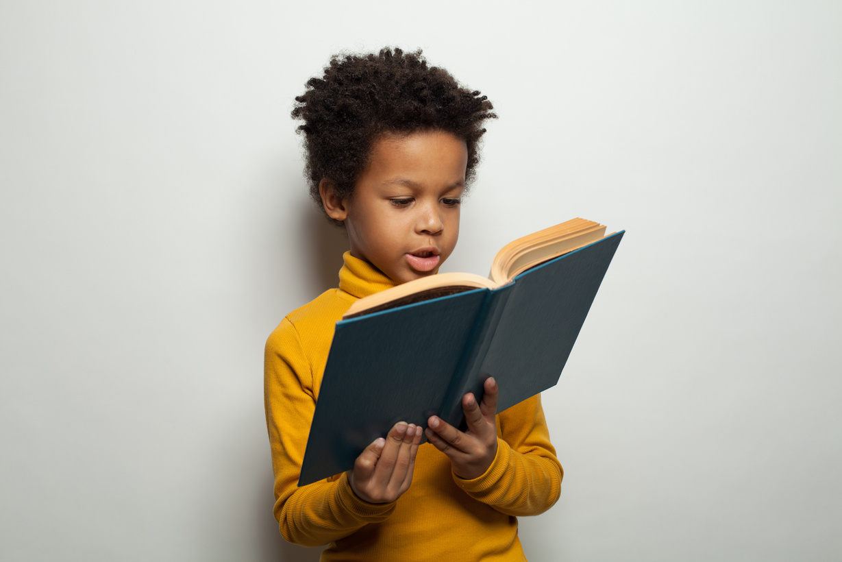 Smart black child boy reading a book on white background